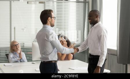 Confident executive shaking hand of successful African American employee Stock Photo