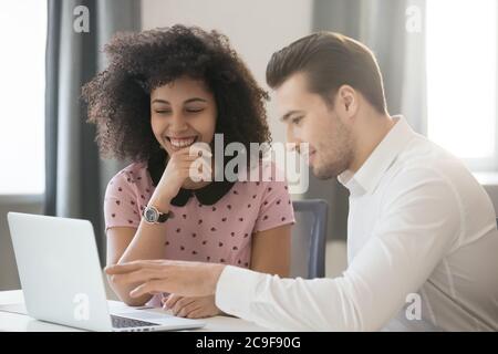 Diverse colleagues working together, using laptop, having fun at work Stock Photo
