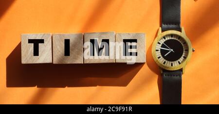 time text on wooden cubes on orange and trendy watch. Business concept Stock Photo