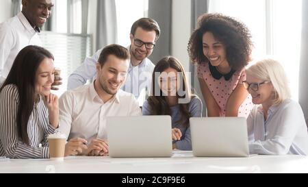 Happy smiling diverse employees using laptop, watching webinar together Stock Photo