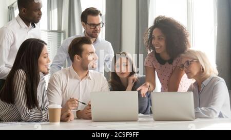 Diverse employees team discussing online project, using laptop at meeting Stock Photo