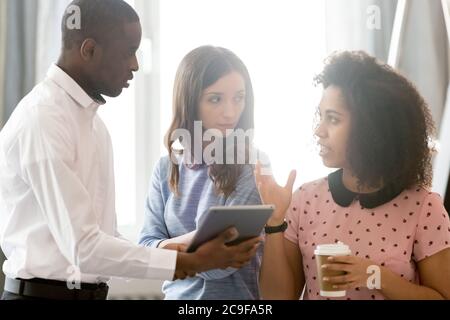 Diverse colleagues employees discussing project, using computer tablet Stock Photo