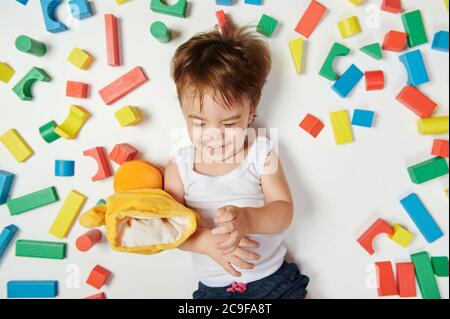 Baby girl playing with toys on colorful bricks background