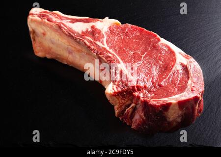 Food concept organic raw steak rib eye or prime rib on black slate board with copy space Stock Photo