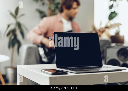 Unrecognizable man sitting on the sofa in his room and playing electric guitar Stock Photo