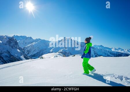 Boy in hiking school stepping on virgin snow enjoying summit view winter activity concept Stock Photo