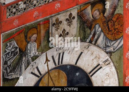 On the timber case of a 14th century striking clock, angels, repainted on wood in the late 15th century, hold up a late 18th century dial.  The clock is said to be one of the oldest timepieces of its type in working condition in the world.  Chapel of St. Theresa of Lisieux in St. Peter’s Cathedral at Beauvais, Oise, Hauts-de-France, France. Stock Photo