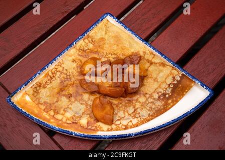Traditional Breton crepe pancake with salted butter caramel sauce and caramelized apples. Brittany, France. Local foodie tourism background. Stock Photo