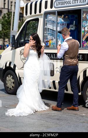 Newly married couple enjoying a 99 ice cream cone on Liverpool seafront. England UK Stock Photo