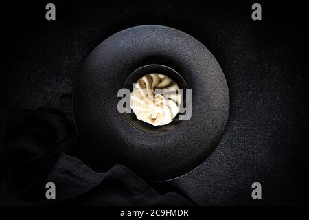 Traditional georgian dampling known as khinkali in georgian on black plate, served with black napkin on black concrete background  with copy space Stock Photo
