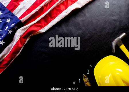 Happy Labor day concept. American flag on dark black background with different construction tools. Copy space for text. Stock Photo