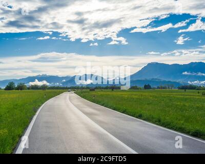 Italy countryside landscape with green grass, road and mountains. Wet asphalt road in Italy countryside. Pordenone, Friuli Stock Photo