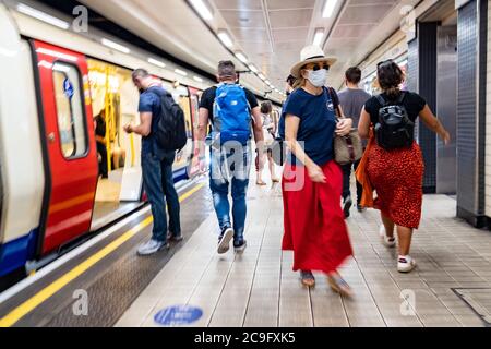 London- July, 2020: Commuters on a London Underground station platform wearing Covid 19 face masks Stock Photo
