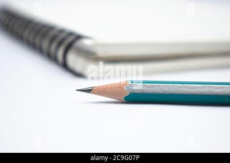 Blue color wood pencil crayon placed in front of a white colored note paper diary Stock Photo