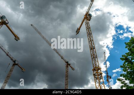 Yellow cranes at the construction site against the cloudy sky Stock Photo