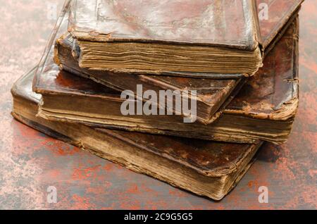 Stack of old and worn leather cover books with gold leaf embossing. Close-up Stock Photo