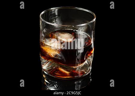 glass with whiskey and two ice cubes photographed in black background