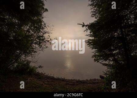 The peeks through morning haze over Lake Wakimi in this northern Ontario Provincial Park. Stock Photo