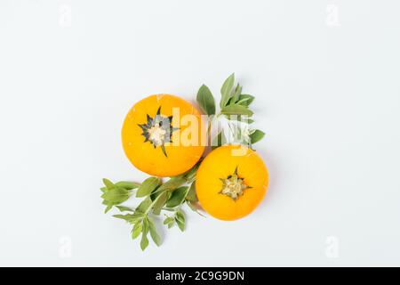 Orange pumpkins with green leaves on white background, flat lay arrangement. Stock Photo