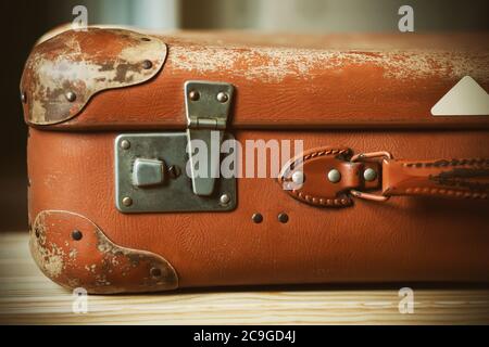 An old brown suitcase with an elegant handle, worn with time, which lies on a wooden bench at the station. Journey. Stock Photo