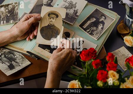 Female hands holding and old photo of her grandfather. Vintage photo album with photos. Family and life values concept. Stock Photo