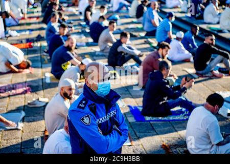 Rotterdam, Netherlands. 31st July, 2020. A policeman stands on guard outside Essalam mosque while wearing a face mask as a preventive measure during Eid al-Adha amid Coronavirus (COVID-19) crisis.Eid al-Adha, also called Eid Qurban or Bakra-Eid, is the second of two Islamic holidays celebrated worldwide each year, and considered the holier of the two. It honours the willingness of Ibrahim to sacrifice his son Ismael as an act of obedience to God's command. Credit: SOPA Images Limited/Alamy Live News Stock Photo