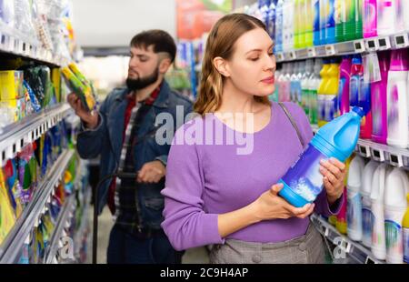 Nice glad pleasant beautiful positive  woman and man in the shop want to buying fabric softener in bottle Stock Photo