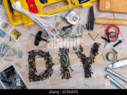 Word DIY lined with metal screws among assorted fasteners, supplies and hand tools on wooden table Stock Photo