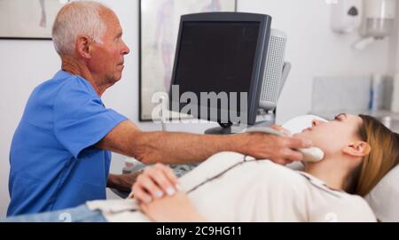 Mature male doctor using ultrasound scan examining female patient in modern hospital Stock Photo
