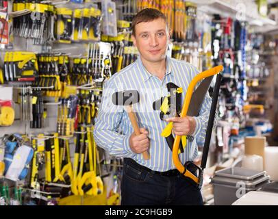 Cheerful man with various tools in the hardware store Stock Photo