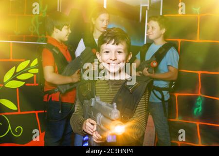 Portrait of happy cheerful positive smiling preteen boy with laser pistol posing in laser tag labyrinth Stock Photo