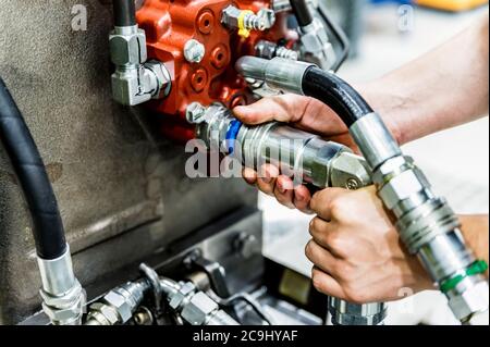 Industrial worker assembles agricultural equipment at plant Stock Photo
