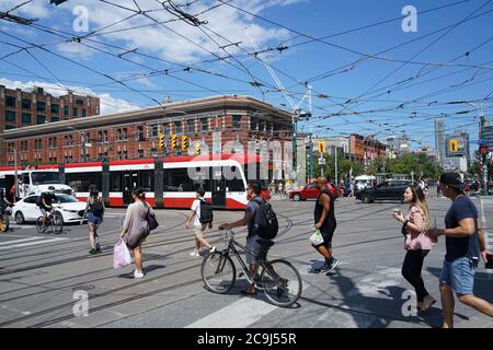 Toronto, Canada - July 31, 2020: Pedestrians and cyclists cross at the busy corner of Queen and Spadina streets. Stock Photo