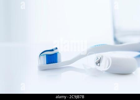 Toothbrush with toothpaste and dental floss against a white background. Stock Photo
