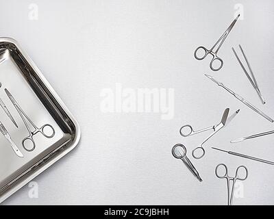 Surgical scissors and tray against a grey background. Stock Photo