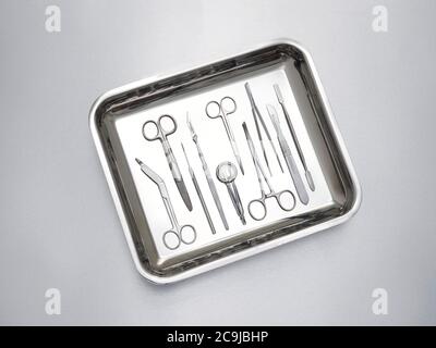 Surgical equipment in a tray against a grey background. Stock Photo