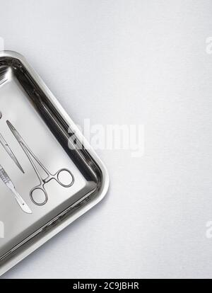 Surgical scissors on a tray against a grey background. Stock Photo