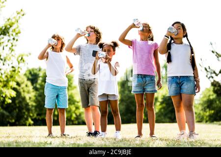 Children drinking water in park.