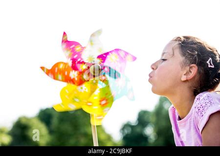 Girl blowing multi coloured paper windmill, close-up. Stock Photo