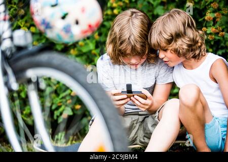 Boys playing games on mobile phone. Stock Photo