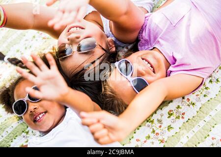 Girls wearing sunglasses and lying on blanket in park. Stock Photo