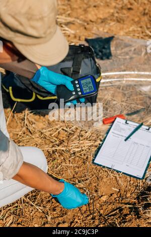 Measuring Soil Temperature with Thermometer. Female agronomist measuring soil temperature in the field