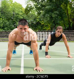 Male and female athletes doing push-ups. Stock Photo