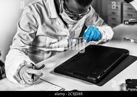 Forensic Science Data. Forensic analyst examining laptop computer. Stock Photo
