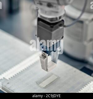 Articulated robotic arm working on a conveyor belt in a high tech factory. Stock Photo