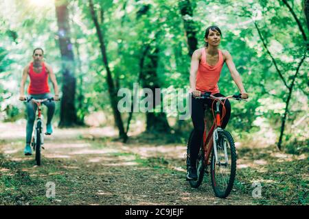 Women riding bikes together in park. Stock Photo