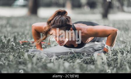 Female athlete doing push-ups outdoors. Stock Photo