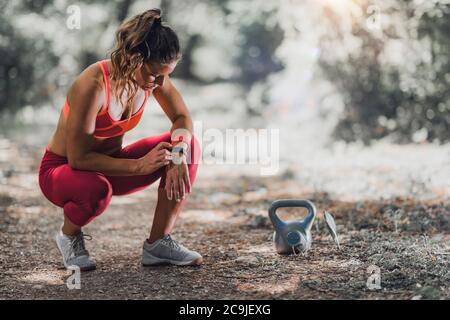 Outdoor exercising. Female athlete using fitness band to track her activities. Stock Photo