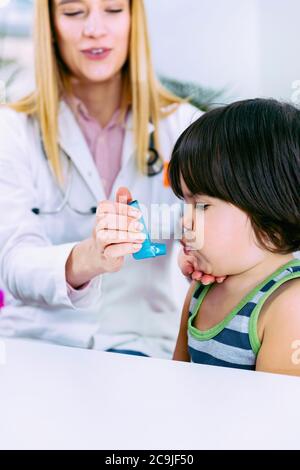 Paediatrician helping boy with asthma inhaler. Stock Photo
