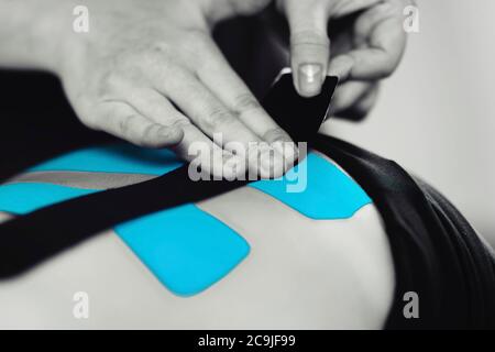 Physical therapist placing kinesio tape on patient's back. Stock Photo